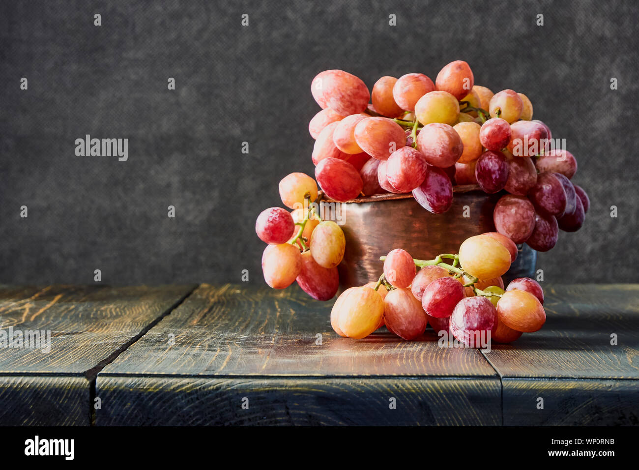 Fresh grapes. Bunches of different varieties in a plate on an old wooden table and dark background. soft focus Stock Photo