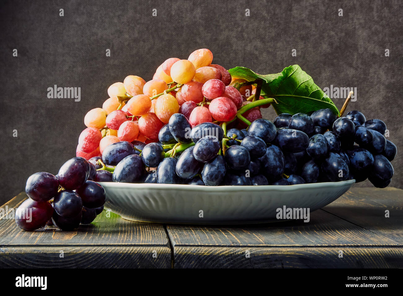 Fresh grapes. Bunches of different varieties in a plate on an old ...
