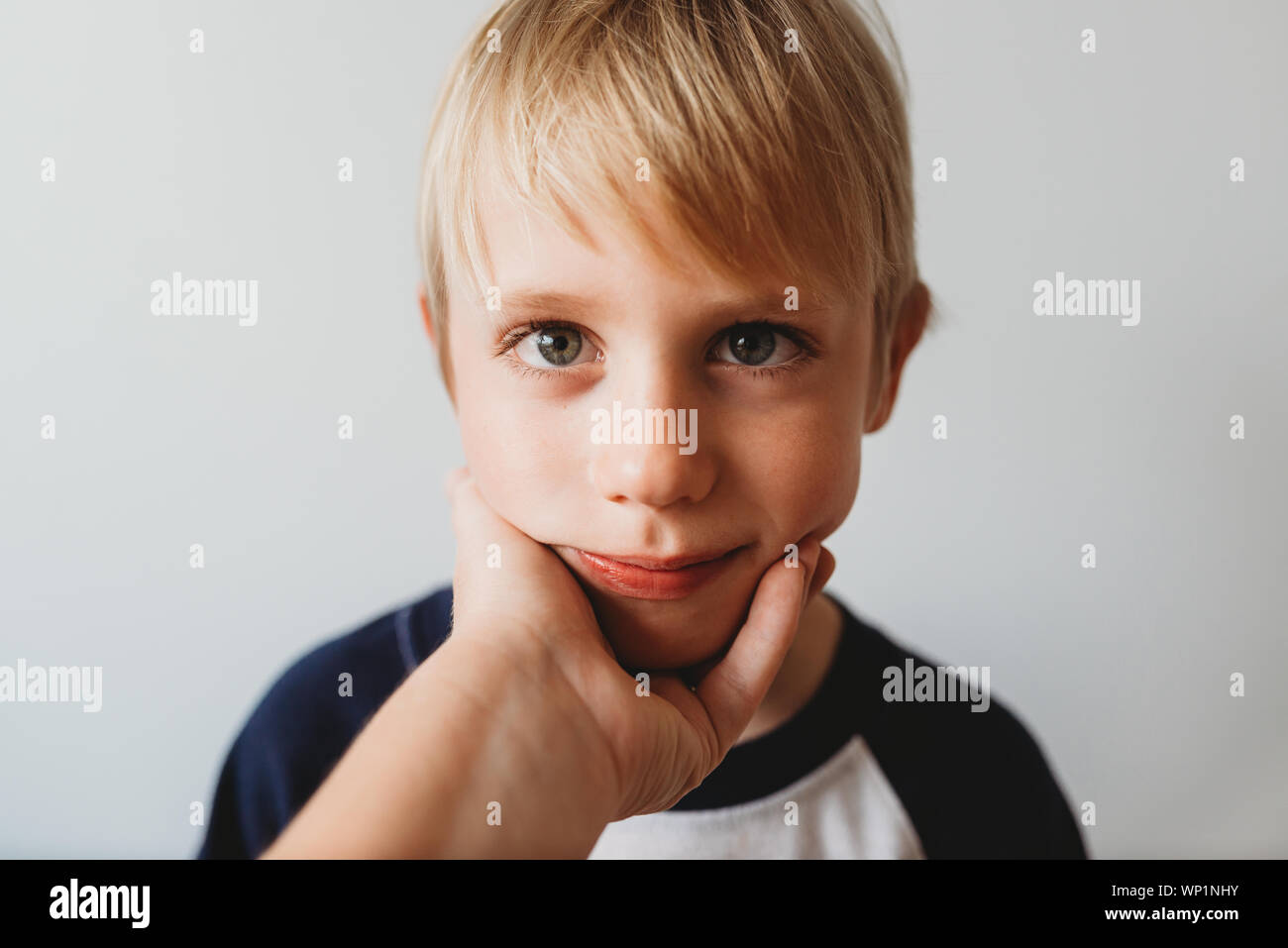 Loving moment of happy son with mother's hand holding his face Stock Photo