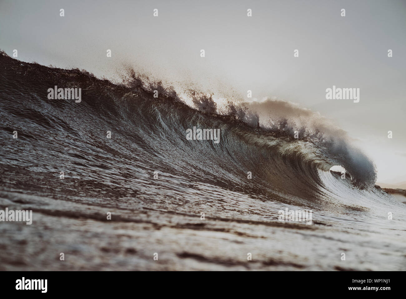Moody scene of a wave breaking at dusk Stock Photo