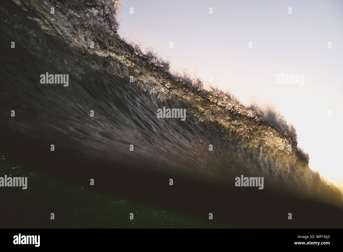 Split image of a backlit wave breaking at sunset Stock Photo