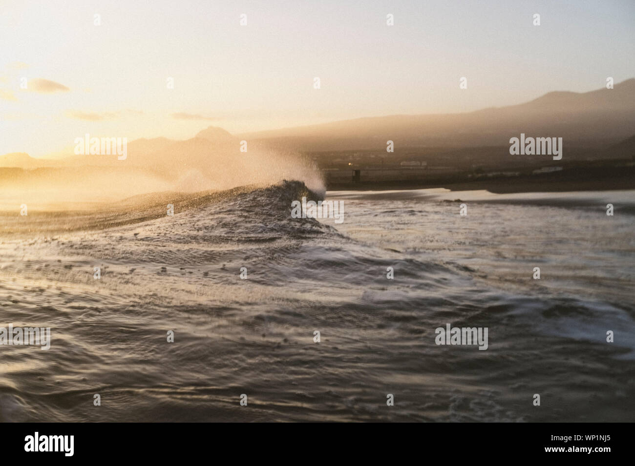 Moody beach scene of a wave breaking with shoreline in background Stock Photo