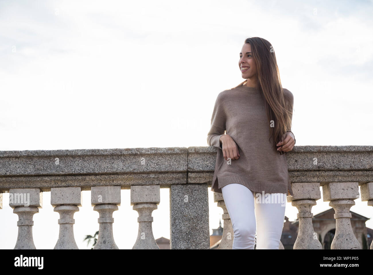 Smiling woman while leaning on the stone railing in Boadilla del Monte Stock Photo