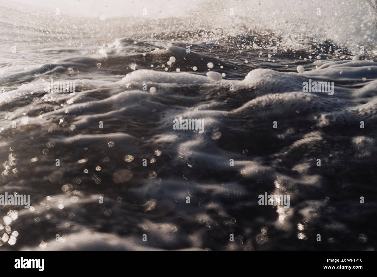 Moody close up of white water and ripples on ocean surface at dusk Stock Photo