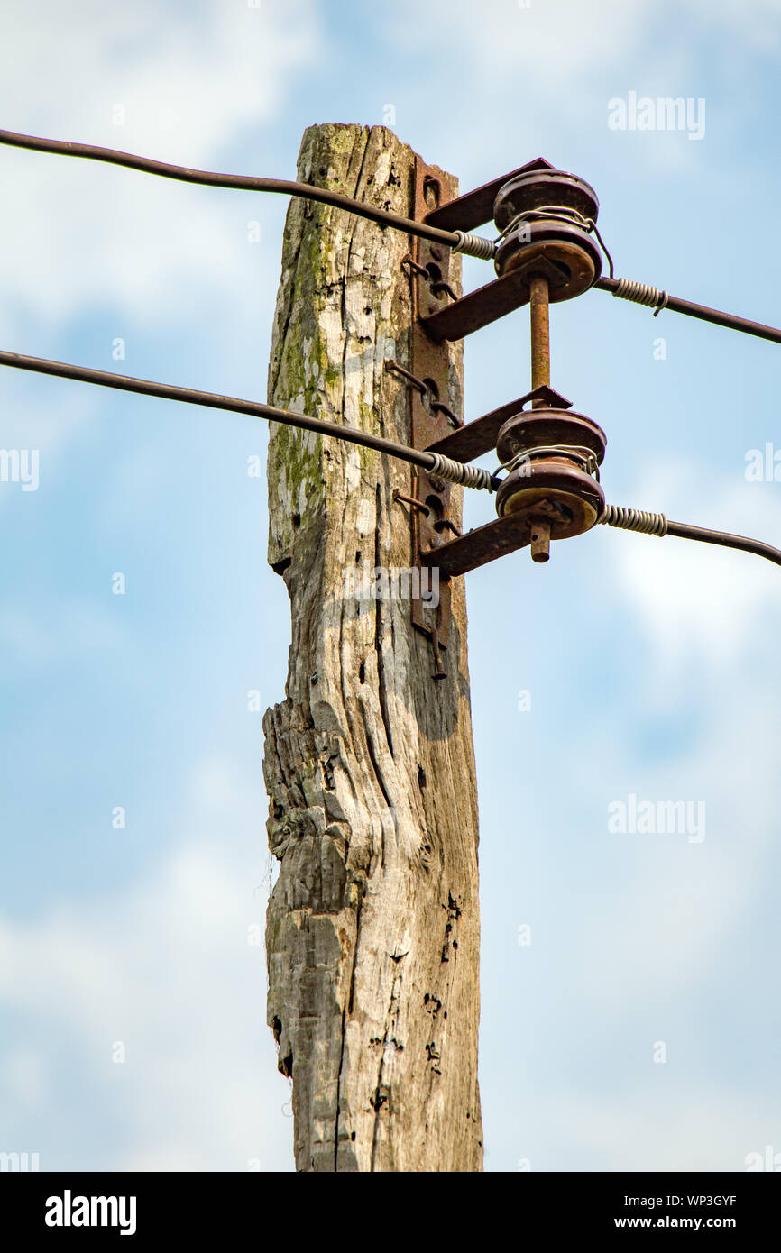 The old wooden pole with wires power line, on blue sky background Stock