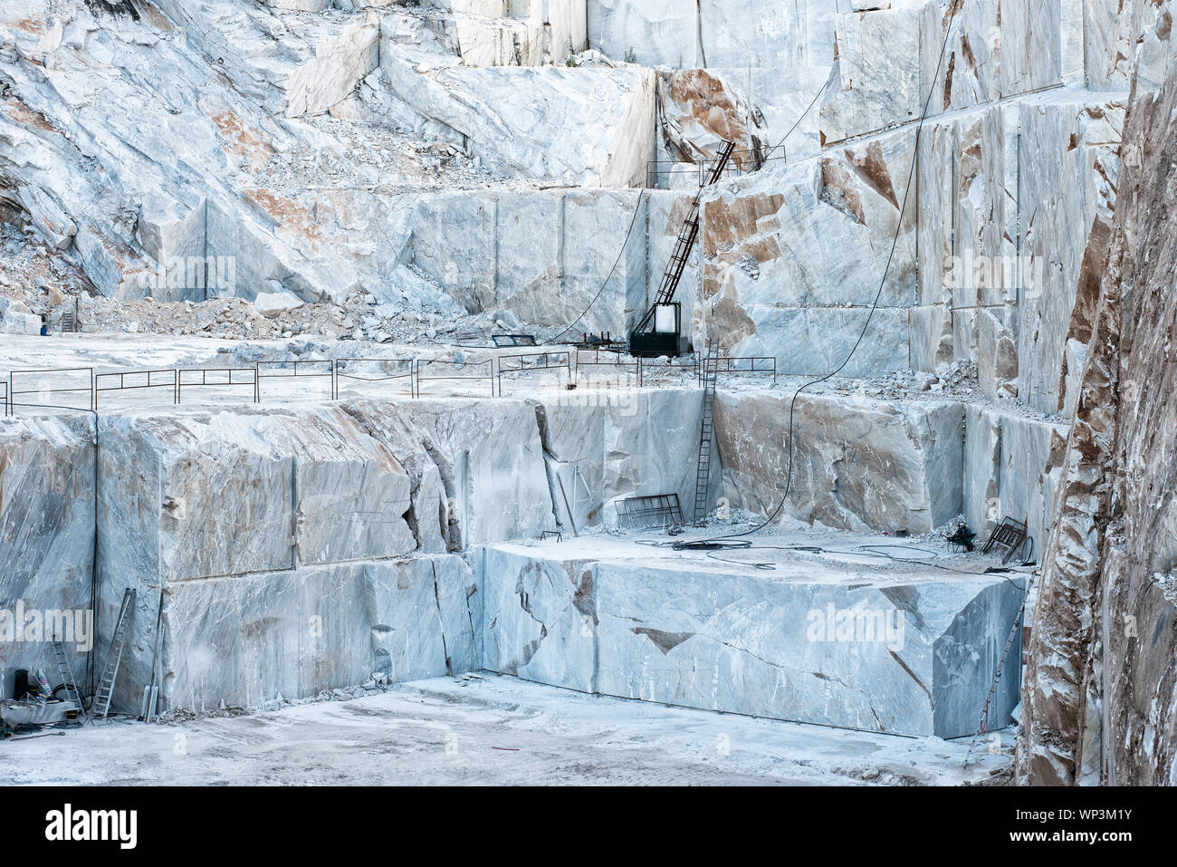 Open cast mine pit with white Carrara marble being cut into rectangular blocks for the construction industry and sculptures in Tuscany, Italy Stock Photo