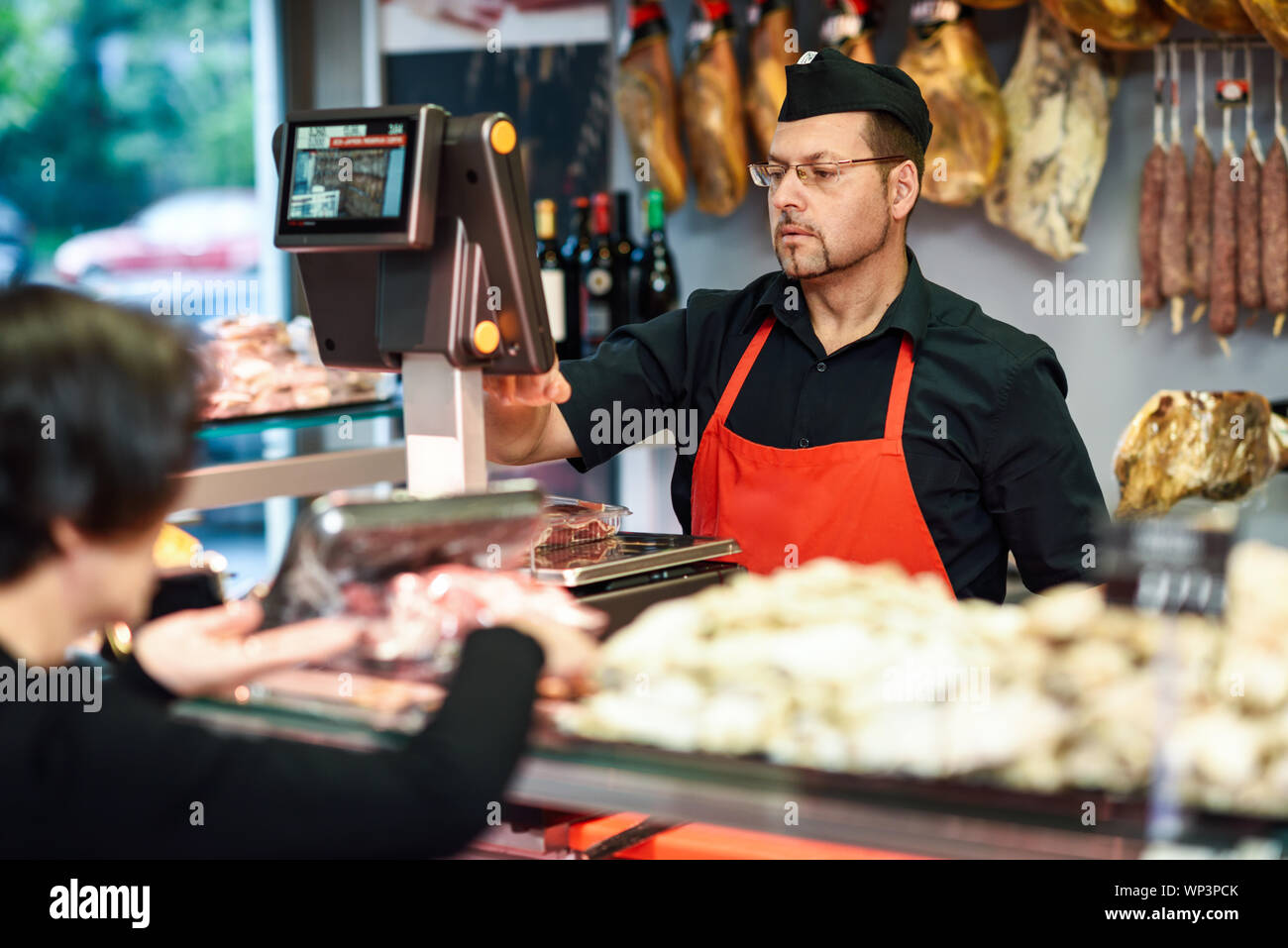 Butcher attending a customer in a butcher's shop Stock Photo - Alamy