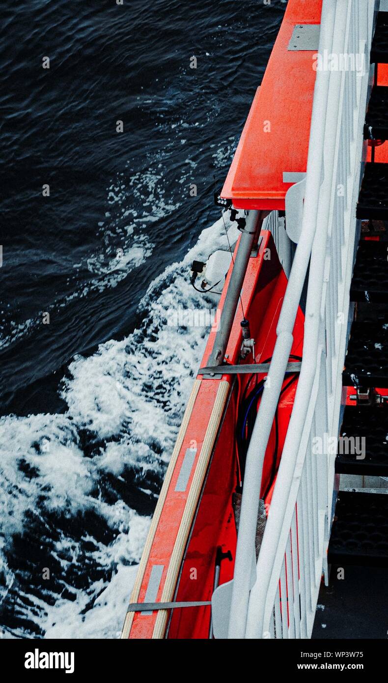 Vertical shot of an orange ship with black staircases in a wavy sea Stock Photo