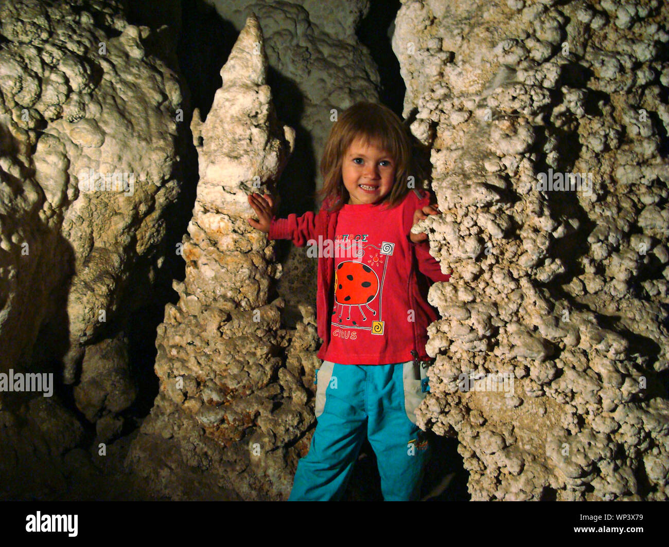 Little girl in a pink blouse and blue pants in a Thai cave between two  stalagmites Stock Photo - Alamy