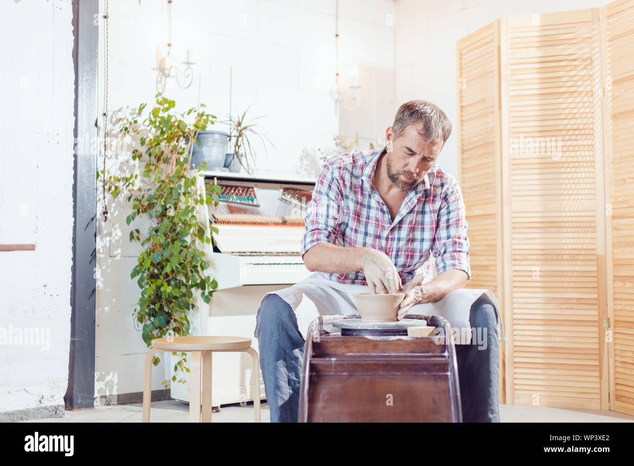 A male potter works on a pottery wheel in a workshop Stock Photo - Alamy