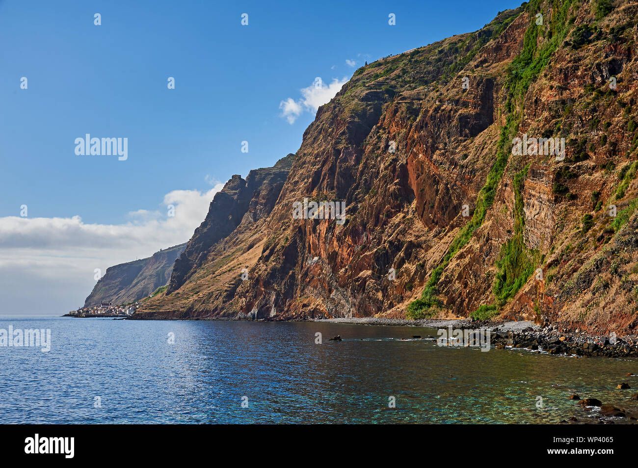 The southern coastline of the island of Madeira includes isolated villages at the foot of extensive sea cliffs. Stock Photo