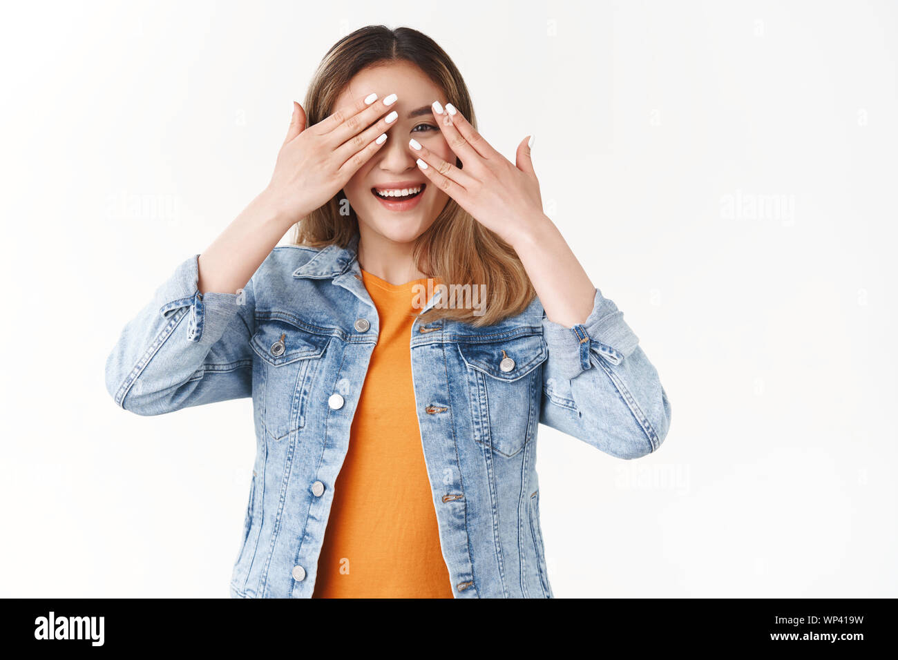 Girl eager see present cannot hold anticipation tempting check out cover eyes peeking through fingers joyful waiitng surprise-gift standing white back Stock Photo