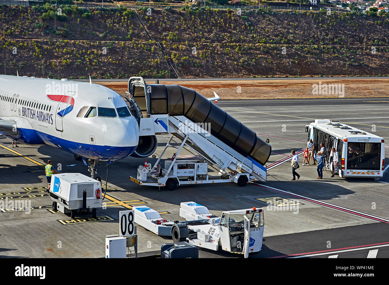 Funchal airport, Madeira and a British Airways jet is preparing for departure, with passengers exiting a transfer bus onto the tarmac. Stock Photo