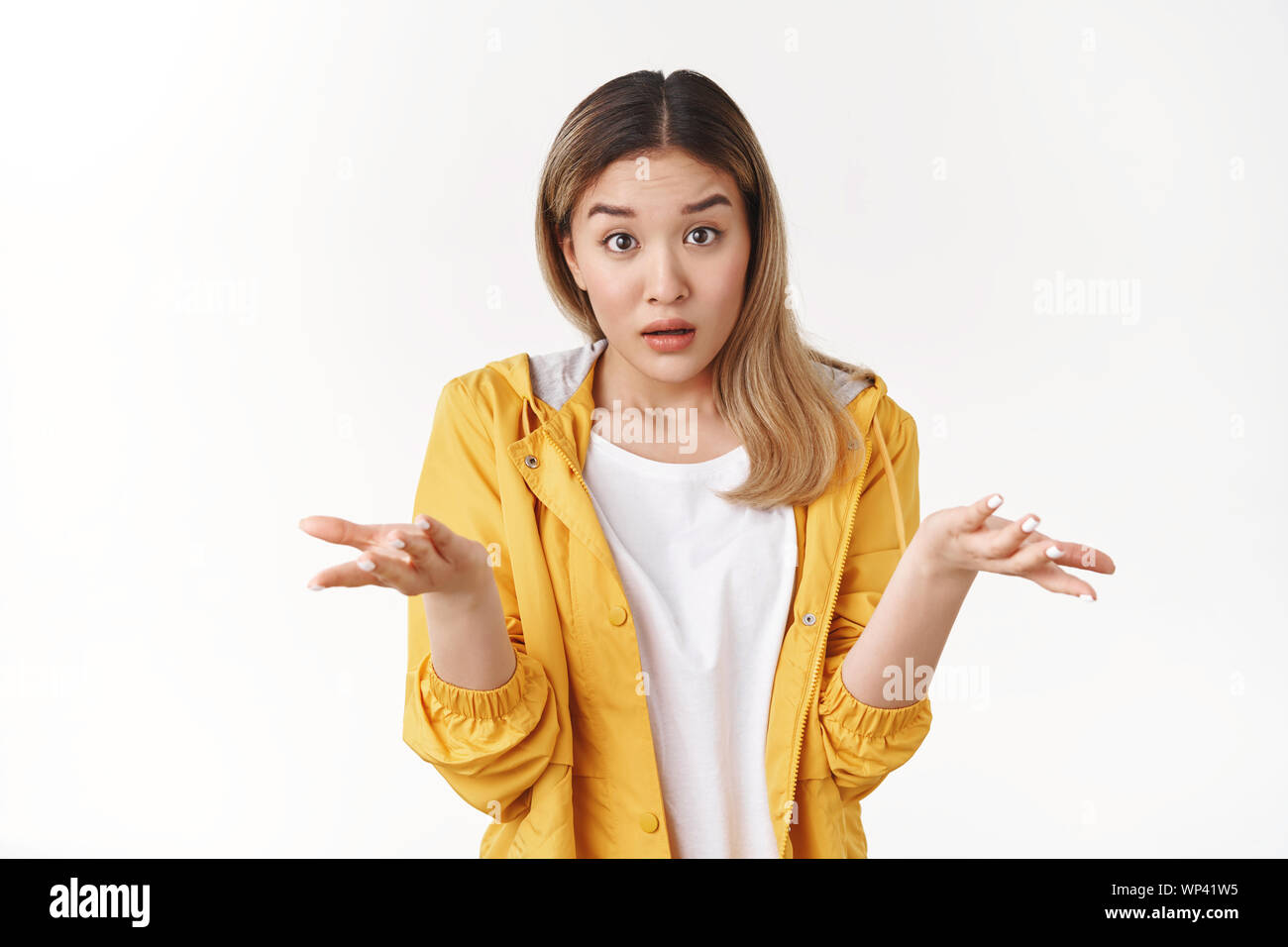 What wrong. Ambushed shocked confused young asian girl coworker shrugging hands spread sideways full disbelief asking question questioned perplexed un Stock Photo