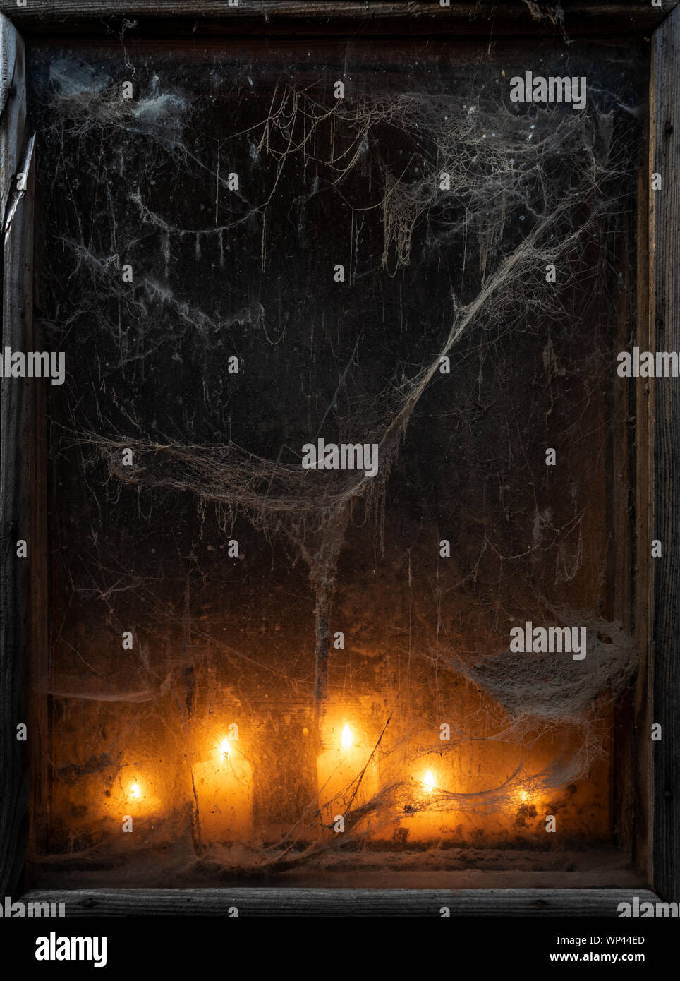 Spooky Halloween background. Scary card with old cobweb and burning candles in the dark Stock Photo