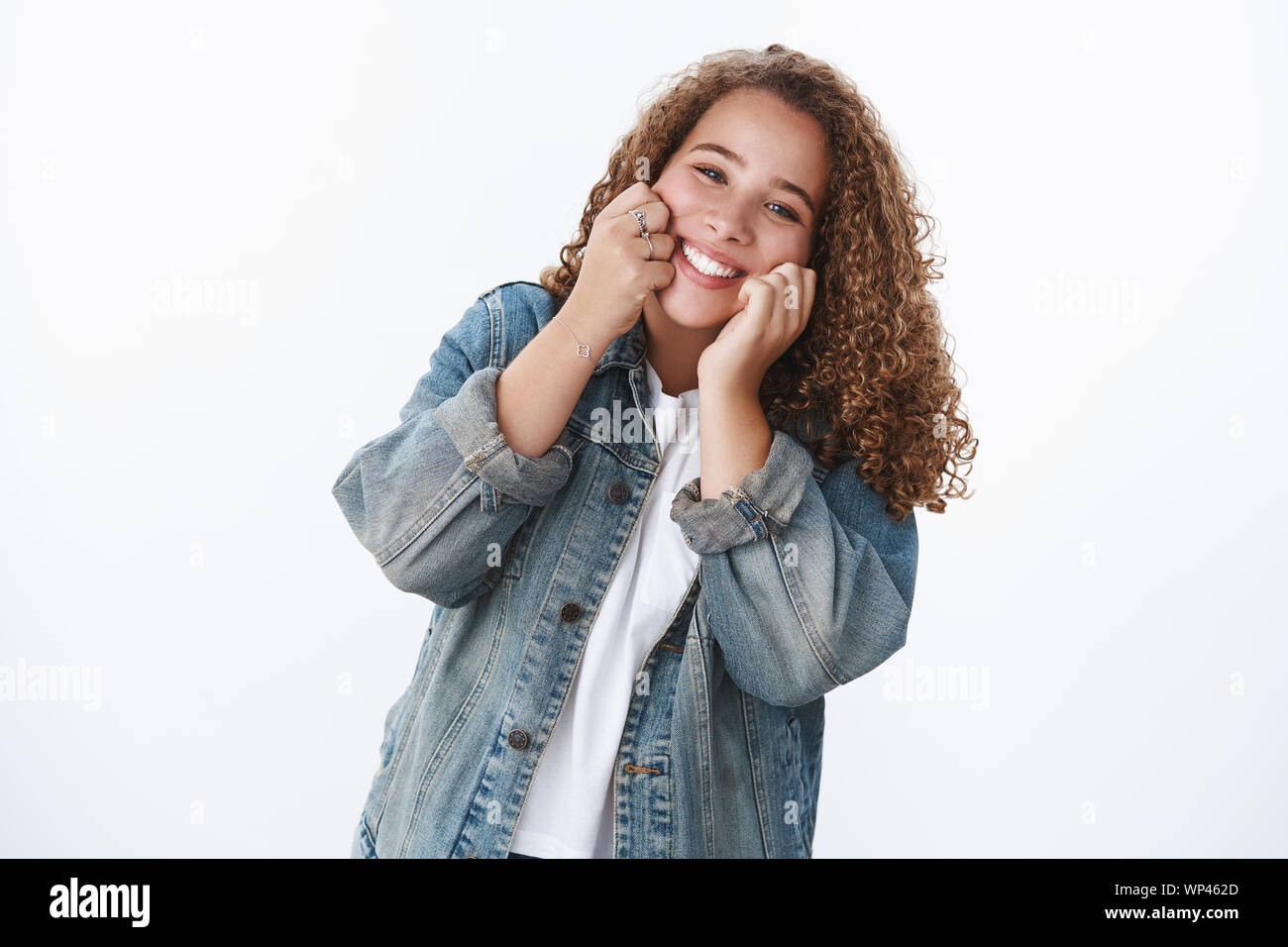 Happy charismatic tender silly chubby cute girl touching cheeks smiling cheerfully have best day enjoy life having fun doing good standing white backg Stock Photo