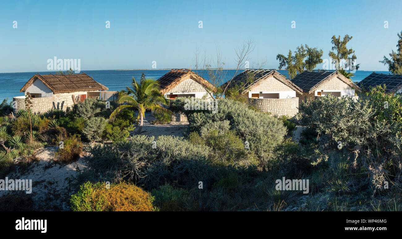 Laguna Blu, Madagascar, July 17, 2019: Rear view of Laguna Blu hotel guest huts in the early morning with spiky bush in the foreground and blue coral Stock Photo
