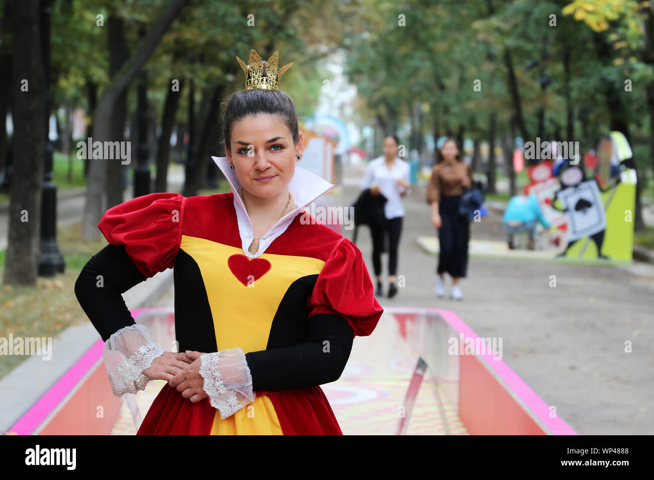 Pretty girl dressed as a Queen of Hearts from the Wonderland poses on Tverskoy Boulevard in Moscow. Character of Lewis Carroll fairy tale Stock Photo