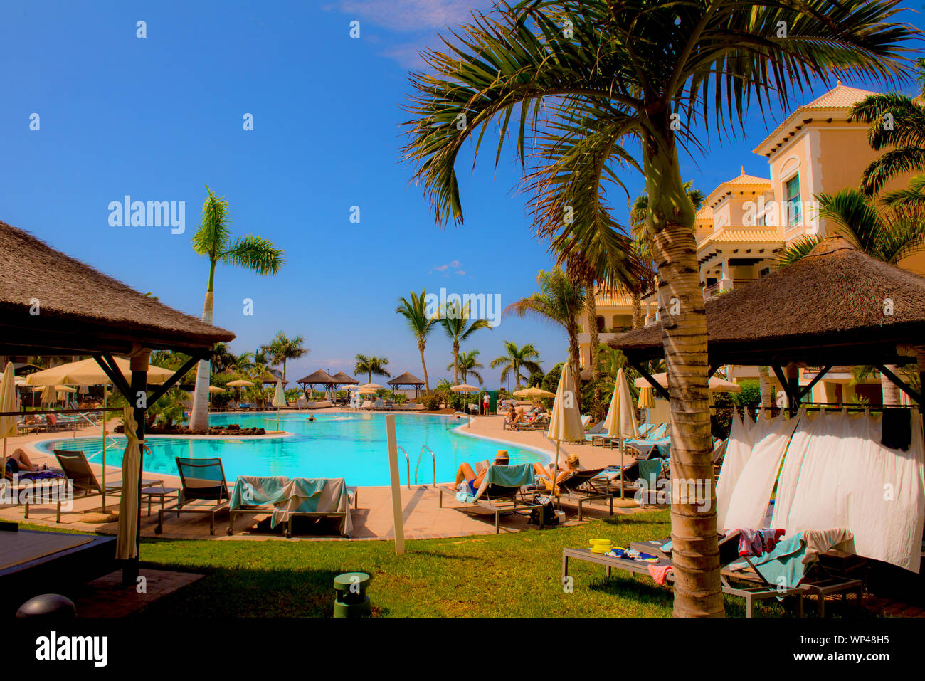 Tenerife, Canary Islands, Spain 6 October 2018: Luxury hotel on the coast with palm trees, swimming Poland unidentified tourists sunbathing. Stock Photo