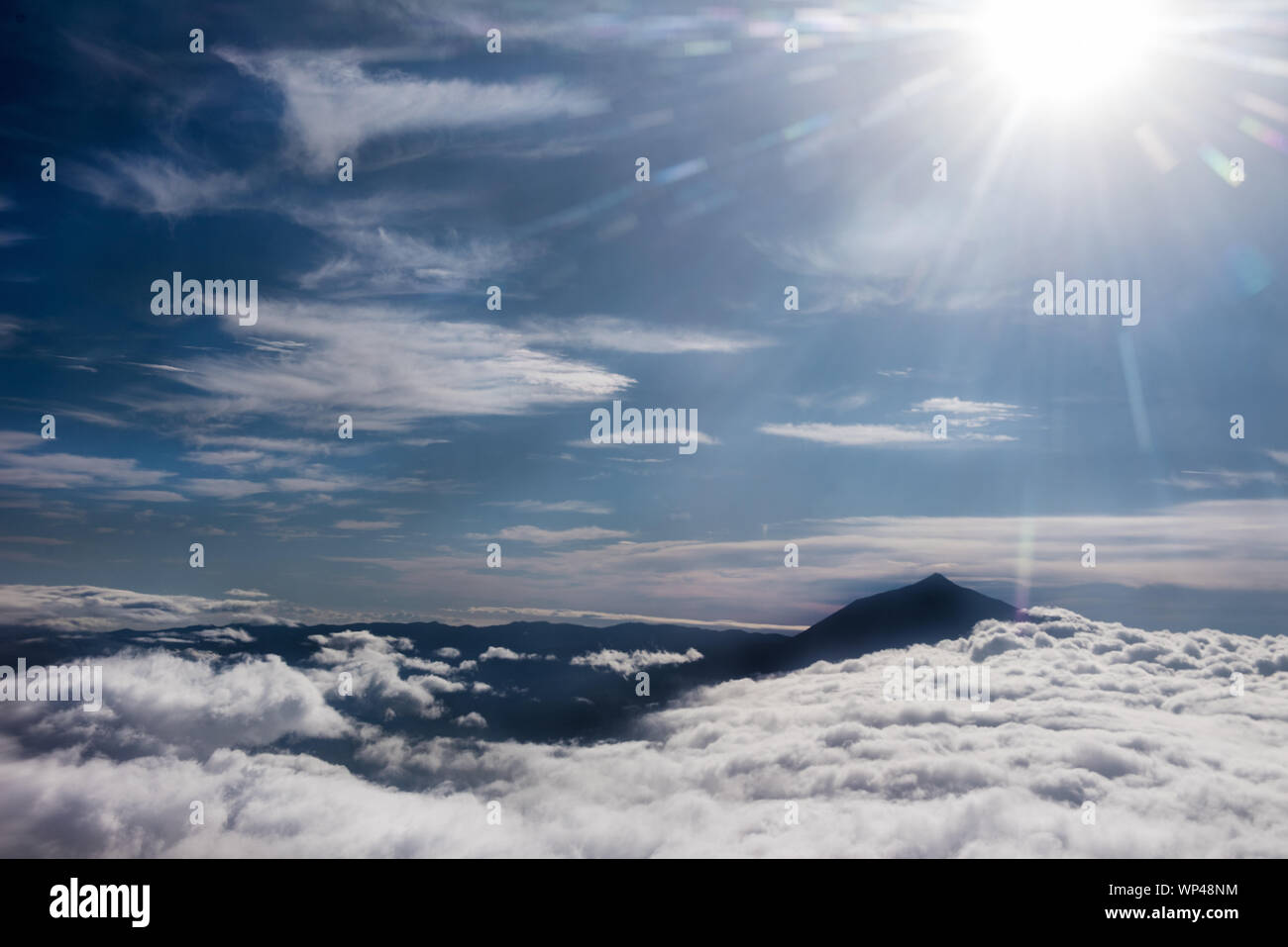 Dramatic view of Mount Teide from the air above the clouds silhouetted the horizon.  Tenerife, Canary Islands, Spain Stock Photo