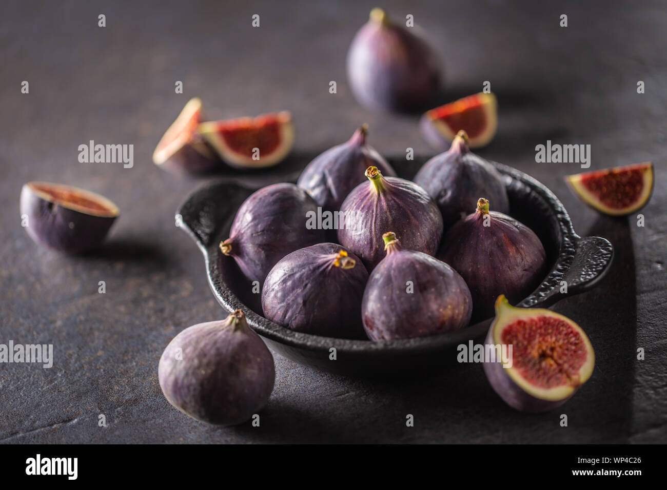 A few figs in a black bowl on an dark concrete table Stock Photo