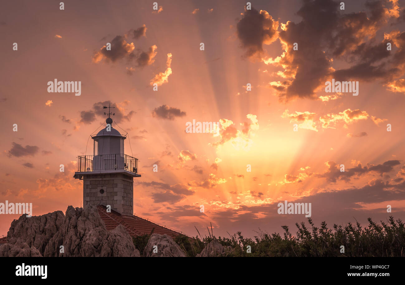 Amazing sunset with sunbeams and lighthouse in Makarska, Croatia Stock Photo