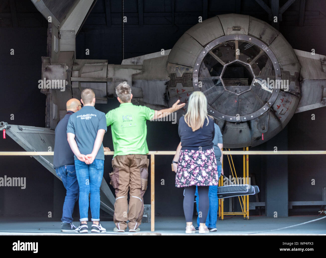 Dassow, Germany. 07th Sep, 2019. Visitors stand in front of the hanganger of the fan project 'Outpost One' in front of the replica of the space interceptor Tie Intercepter. The 1,300 square metre exhibition will be officially opened this weekend. With attention to detail and perfectionism, space fans have created a gigantic 'Star Wars' world. The visitor walks through 29 reconstructed set scenes of the cult film series. Since the beginning of July, trained staff has been guiding groups of visitors through the exhibition. Credit: dpa/Alamy Live News Stock Photo