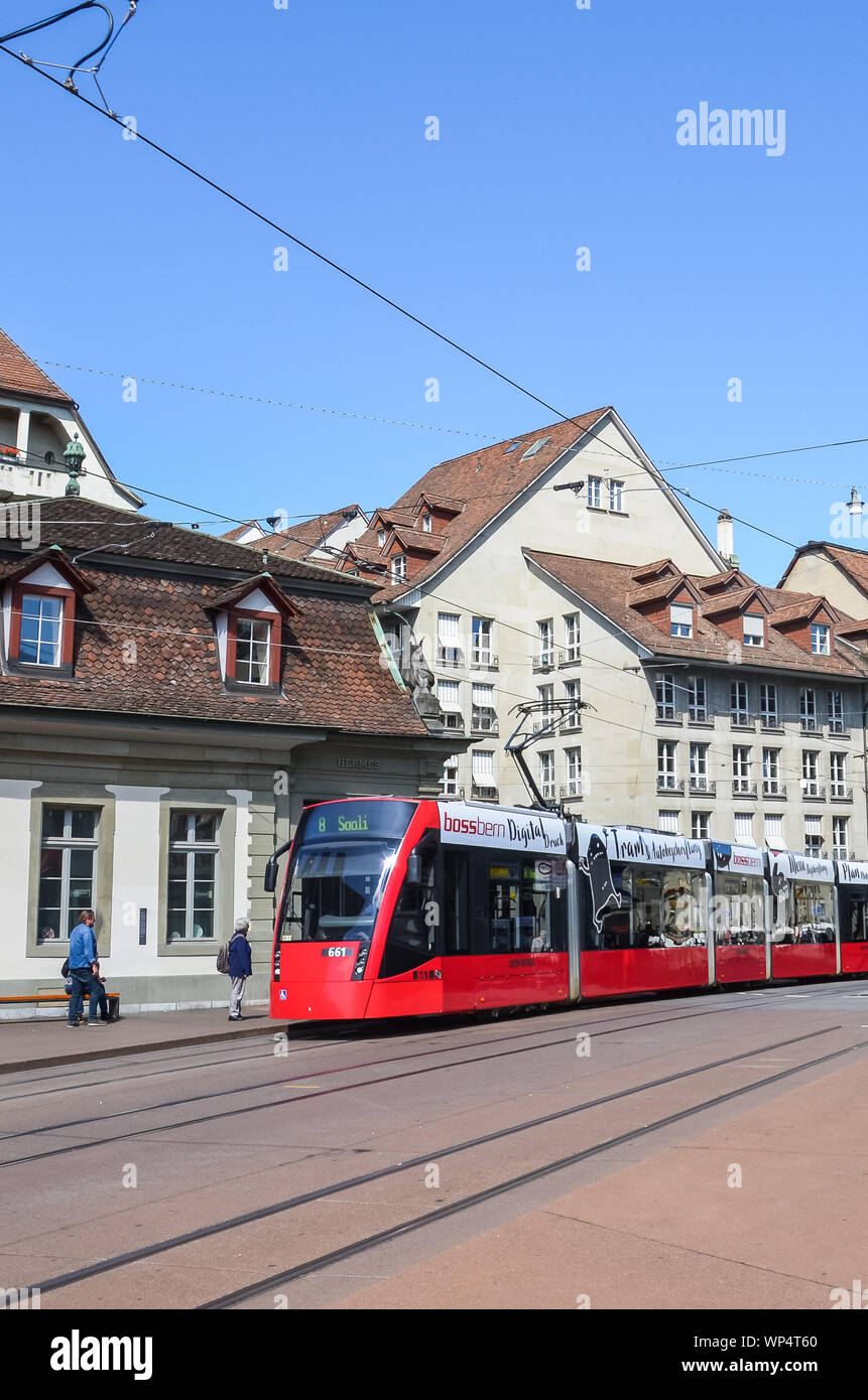 Bern, Switzerland - August 14, 2019: Red tram on the street in the city center of the Swiss capital. Public transport. Trams, transportation. Tram station. Historical buildings. People on the street. Stock Photo