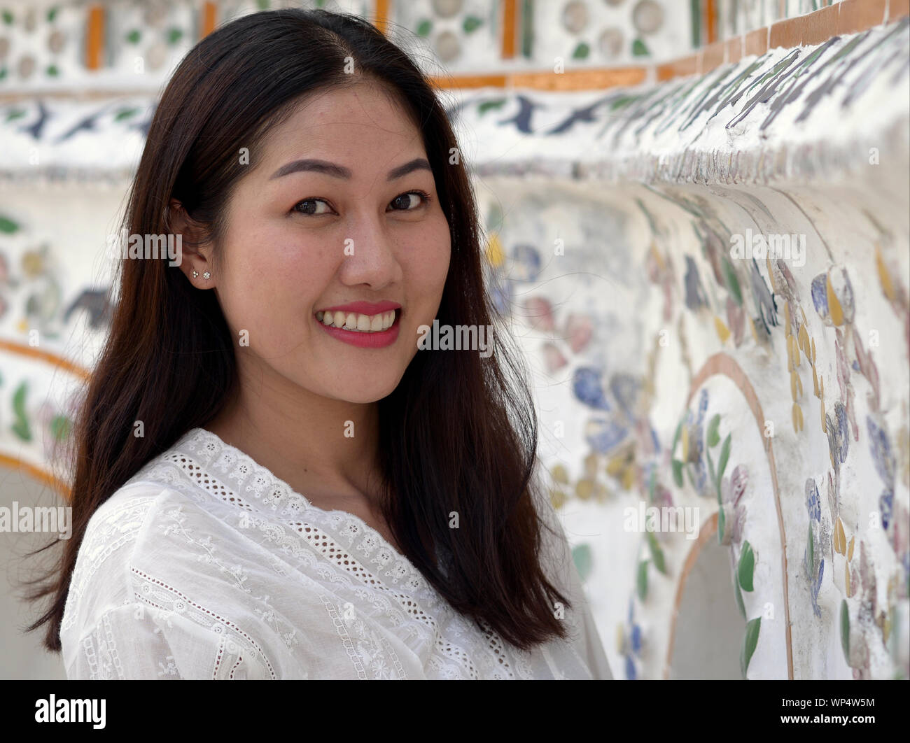 Beautiful young Thai woman smiles for the camera at Bangkok’s Wat Arun temple. Stock Photo