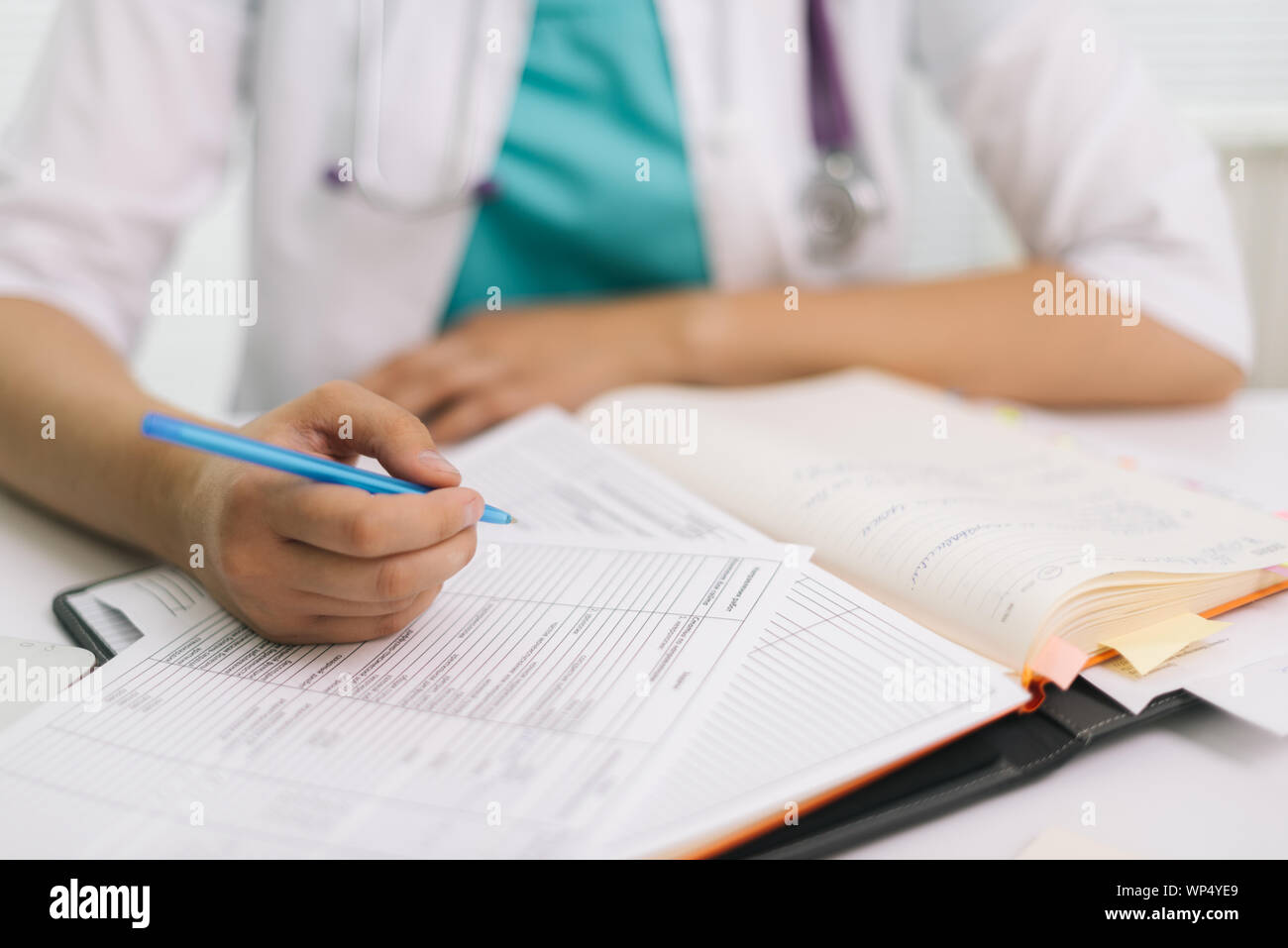 Close-up of woman doctor in office filling out application form Stock ...