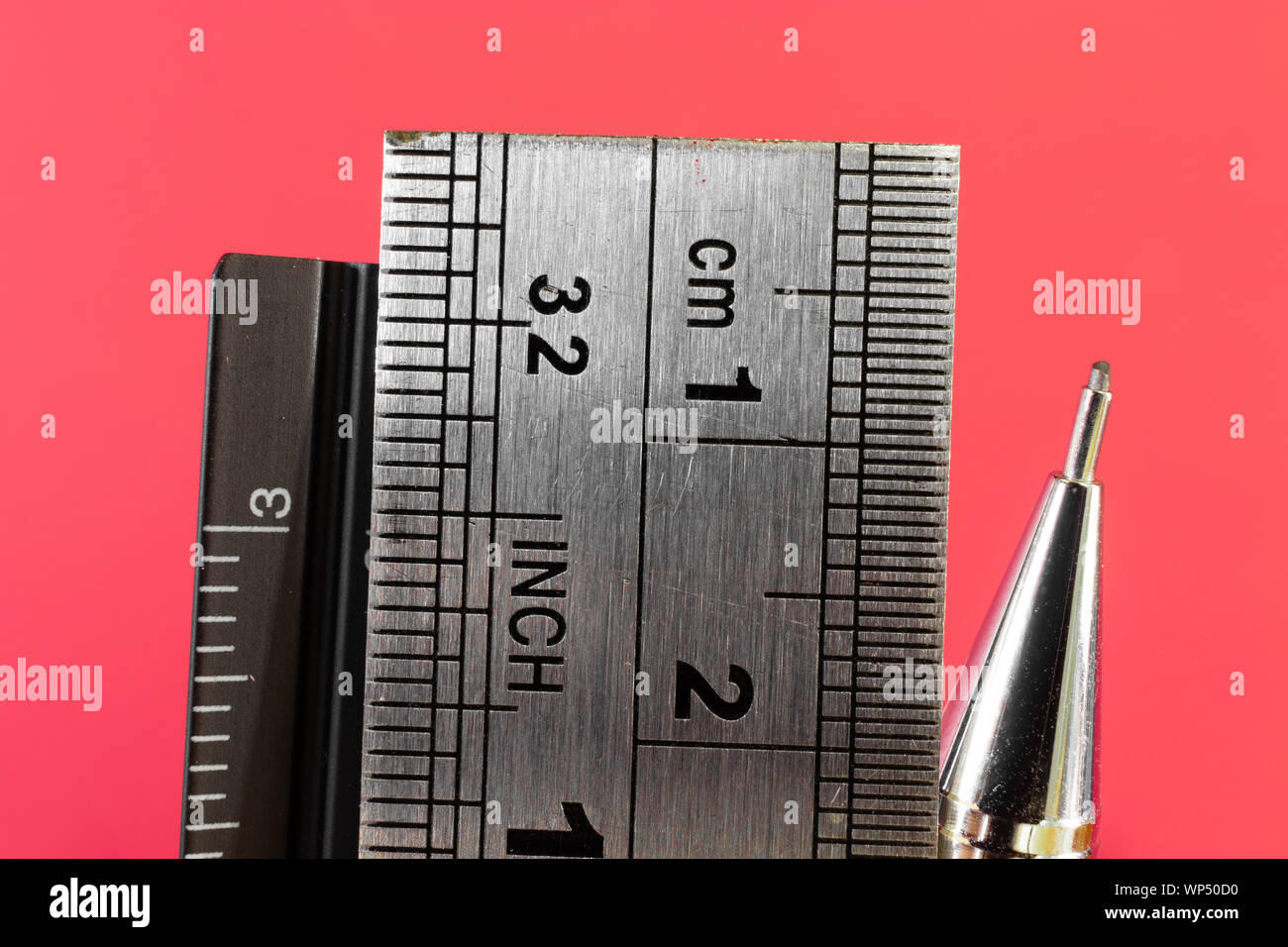 Rulers and mechanical pencil macro image in red background. High quality steel technical drawing tools with different measuring scales. Stock Photo