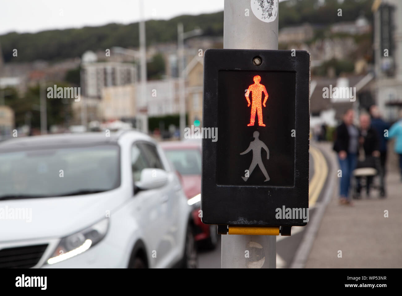 Red and Green man at a pedestrian crossing as cars wait for the lights to change. Stock Photo
