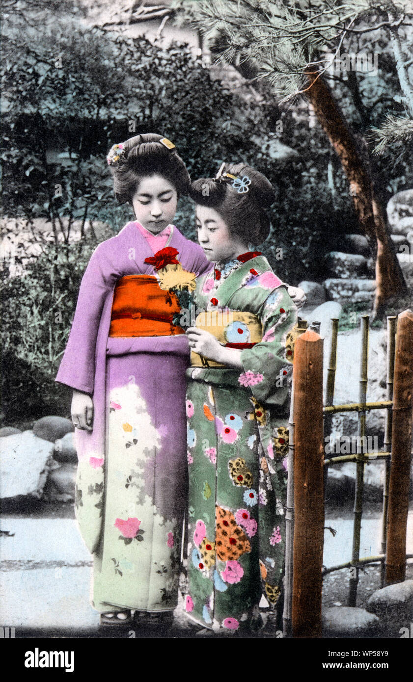 [ 1910s Japan - Japanese Women in Kimono ] —   Two women in kimono and traditional hairstyles. One of them is holding chrysanthemums.  20th century vintage postcard. Stock Photo