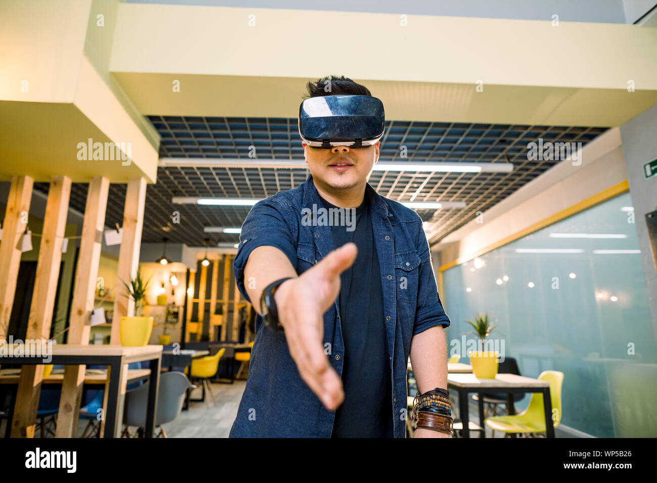 Young Chinese businessman working in office with virtual reality glasses on  head. Man using VR headset for handshaking in augmented reality Stock Photo  - Alamy