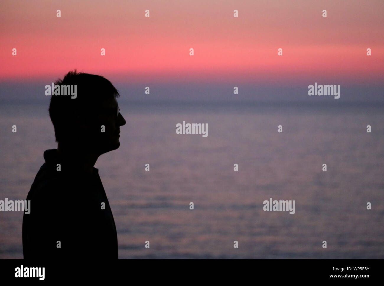 black profilo of young man at sunset and the sea on background Stock Photo