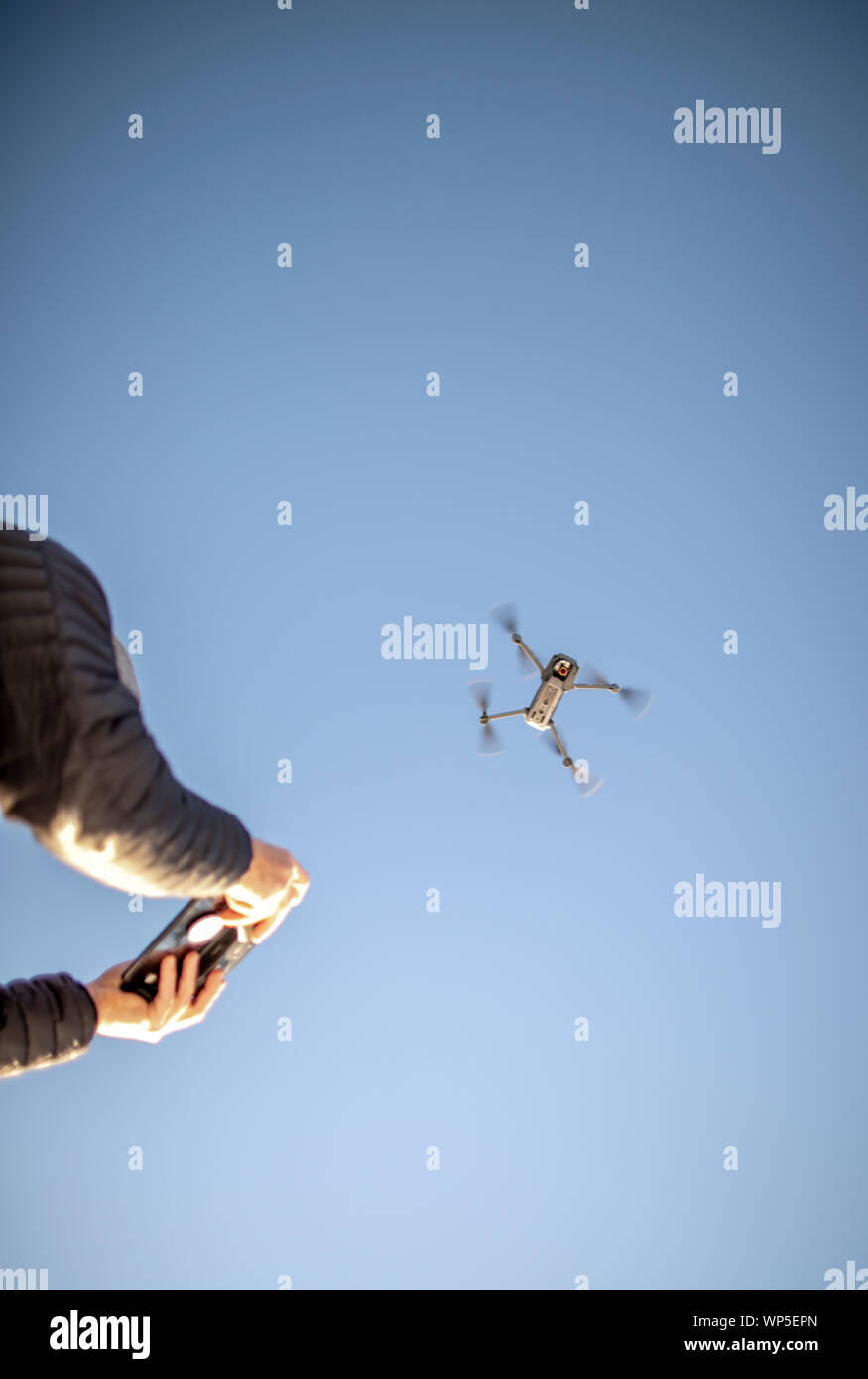 A drone and its remote control are seen against the blue sky. Stock Photo