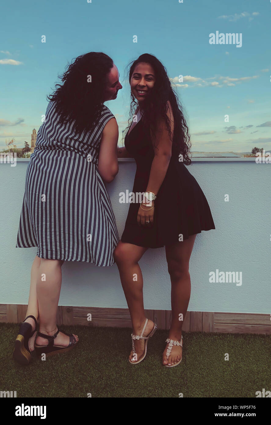Caucasian woman and Latin mulatto woman laughing on a terrace in Spain Stock Photo