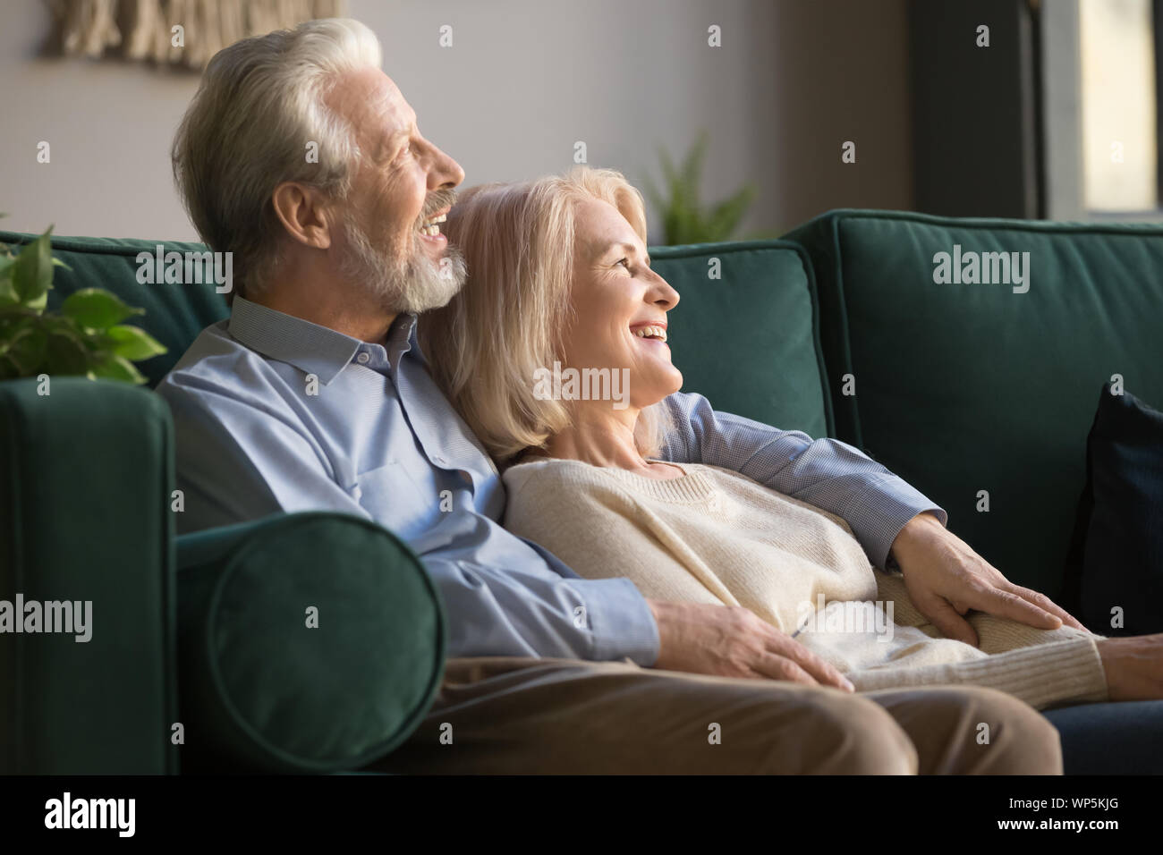 Elder happy smiling retired family couple relaxing on couch. Stock Photo