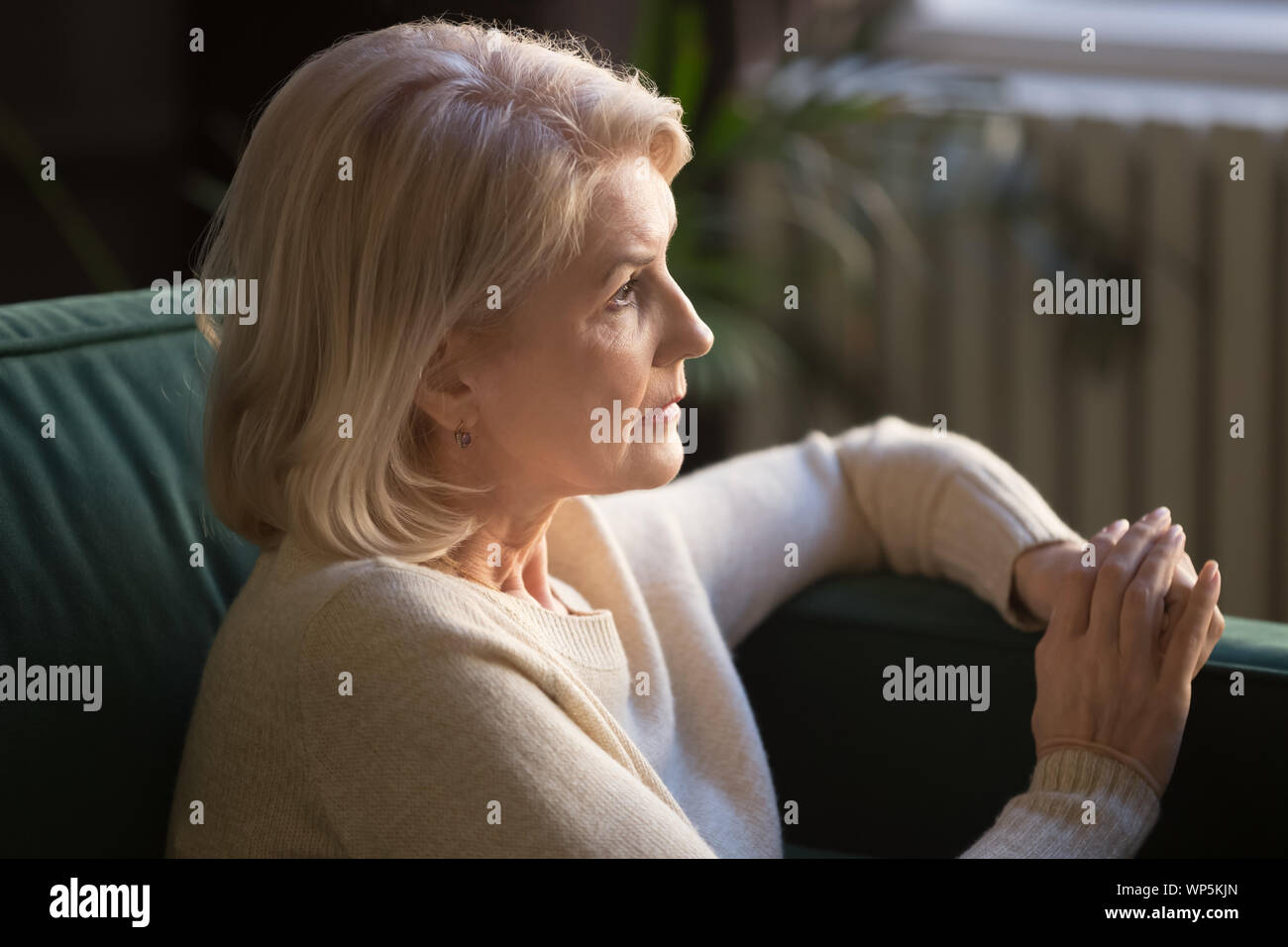 Pensive elderly woman look in distance thinking or mourning Stock Photo