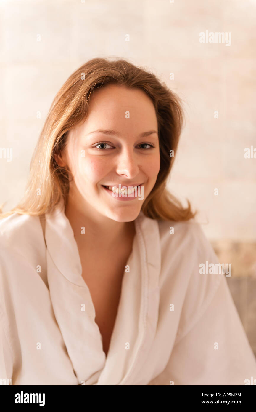 Beautiful young woman in a spa dressed in a white terry cloth robe waiting for a massage. Stock Photo