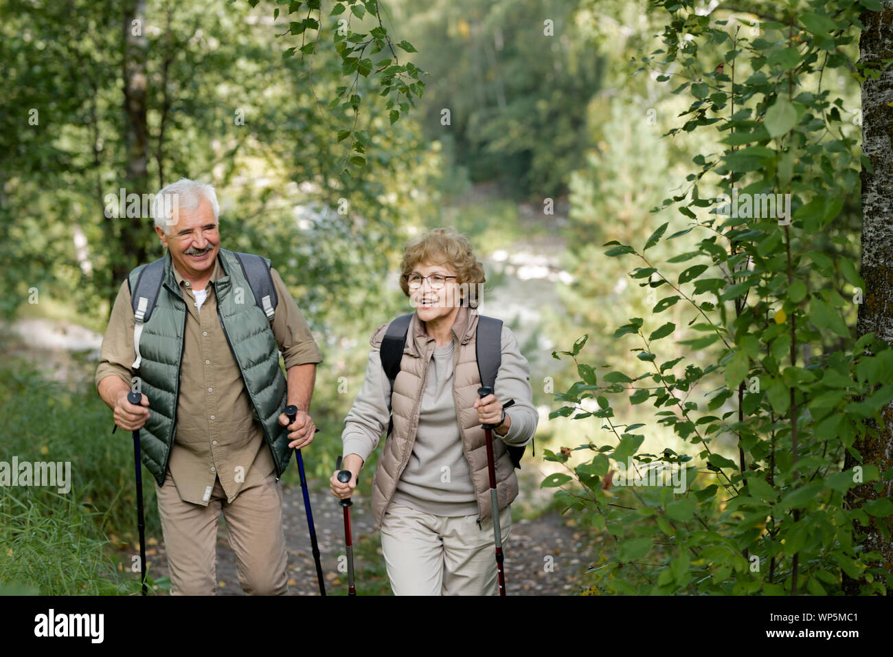 Cheerful mature active couple enjoying trekking in the forest or park Stock Photo