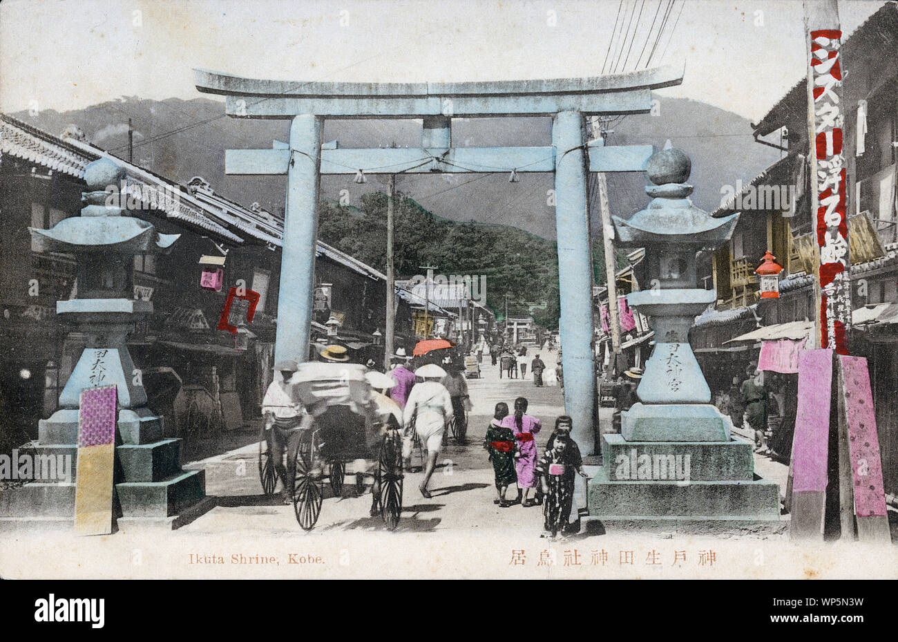 [ 1900s Japan - TITLE ] —   Stone lanterns and a scared torii gate at the entrance way to Ikuta Jinja, a Shinto shrine in Kobe, Hyogo Prefecture.  Lots of shops line the street. The shrine is among the oldest shrines in Japan and is mentioned in the Nihon Shoki, the second oldest book of classical Japanese history.  The Battle of Ichi-no-Tani (1184) took place in and around Ikuta Shrine.  20th century vintage postcard. Stock Photo