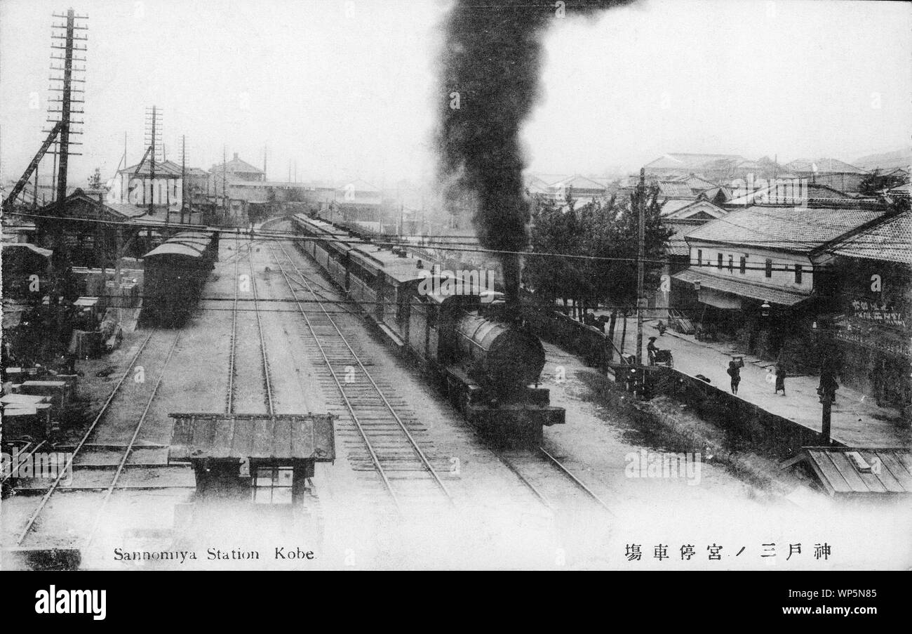 [ 1910s Japan - Japanese Steam Locomotive in Kobe ] —   A steam locomotive pulling passenger cars leaves Sannomiya Station, seen in the back, in Kobe, Hyogo Prefecture on the way to Osaka.  The railroad connection between Kobe and Osaka was opened in May 1874.  Sannomiya Station is still in its old location in this photo. It was moved to its current location on October 10, 1931. The old Sannomiya Station was reopened in 1934 as Motomachi Station.  20th century vintage postcard. Stock Photo