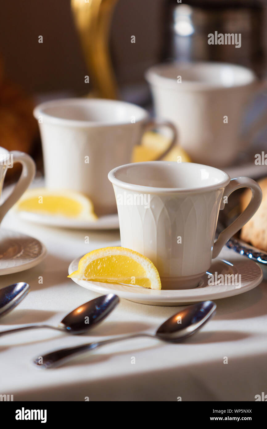 Tea cup sitting on a saucer with a lemon wedge Stock Photo - Alamy