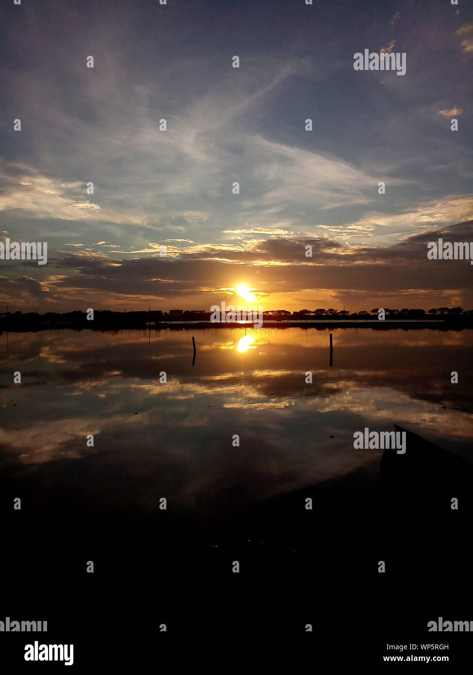 Sunset on cloudy blue sky with water reflections, Landscape Stock Photo