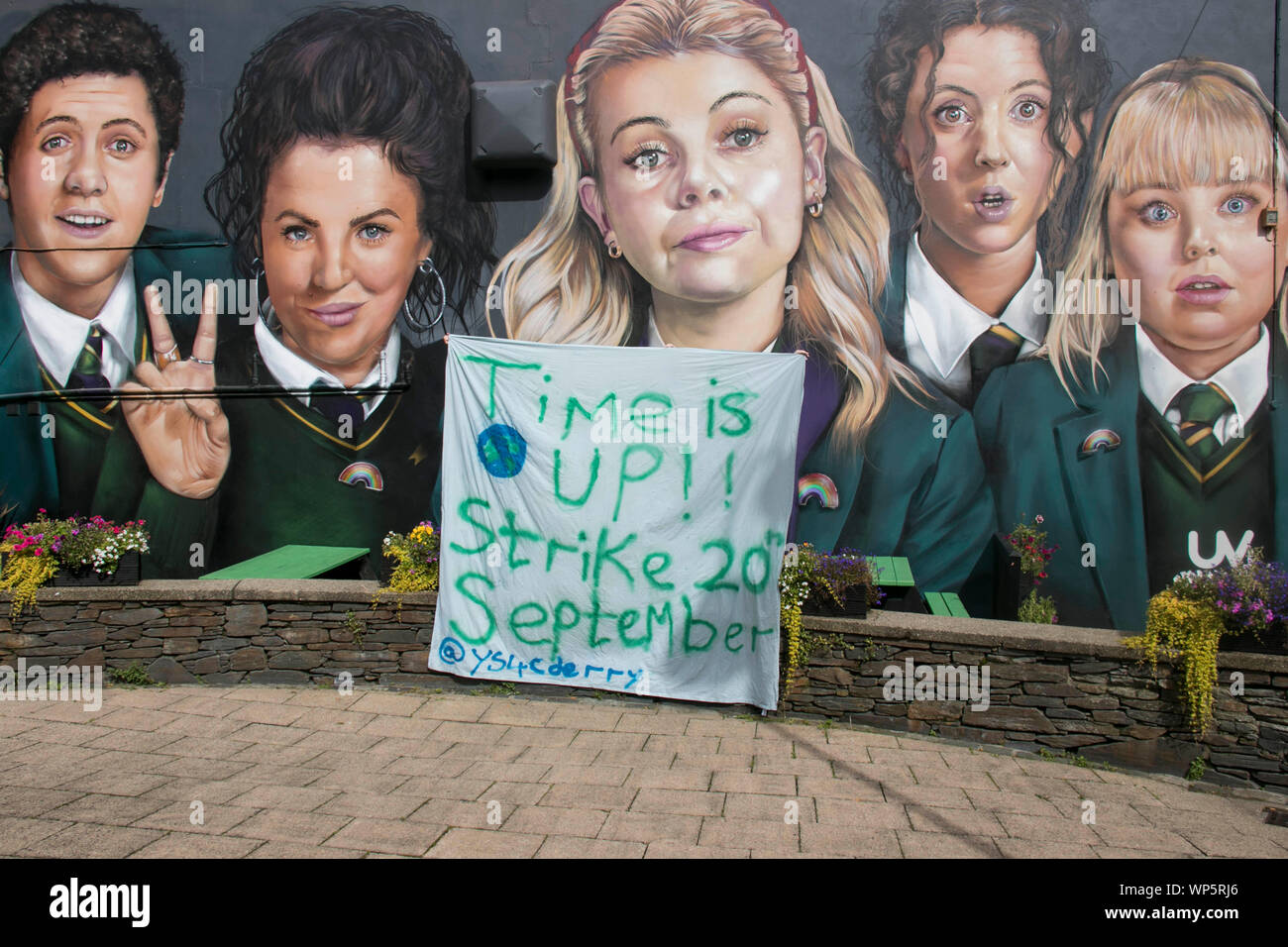 Young climate change activists with their banner advertising teh climate change strike on 20 Spetember in front of the Derry Girls mural. Stock Photo