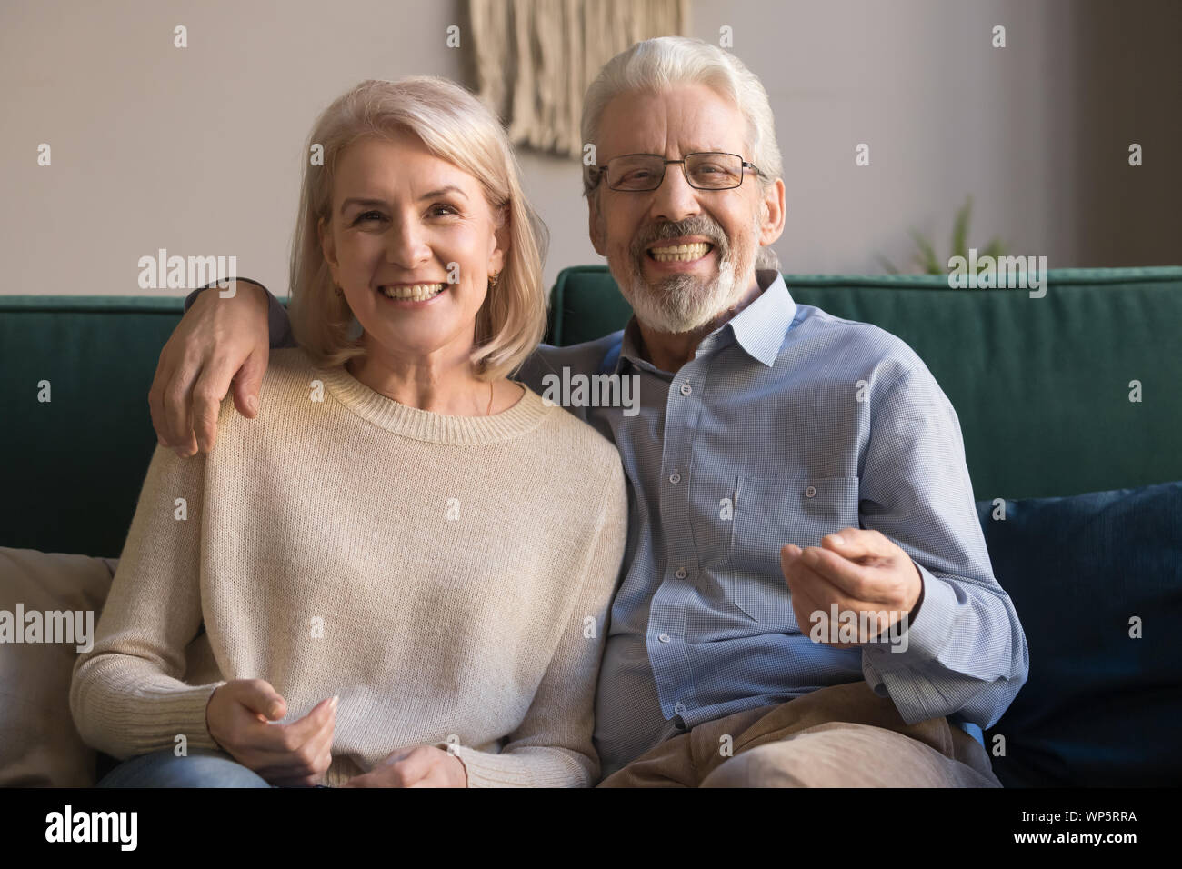 Headshot portrait of smiling mature couple sit on couch Stock Photo