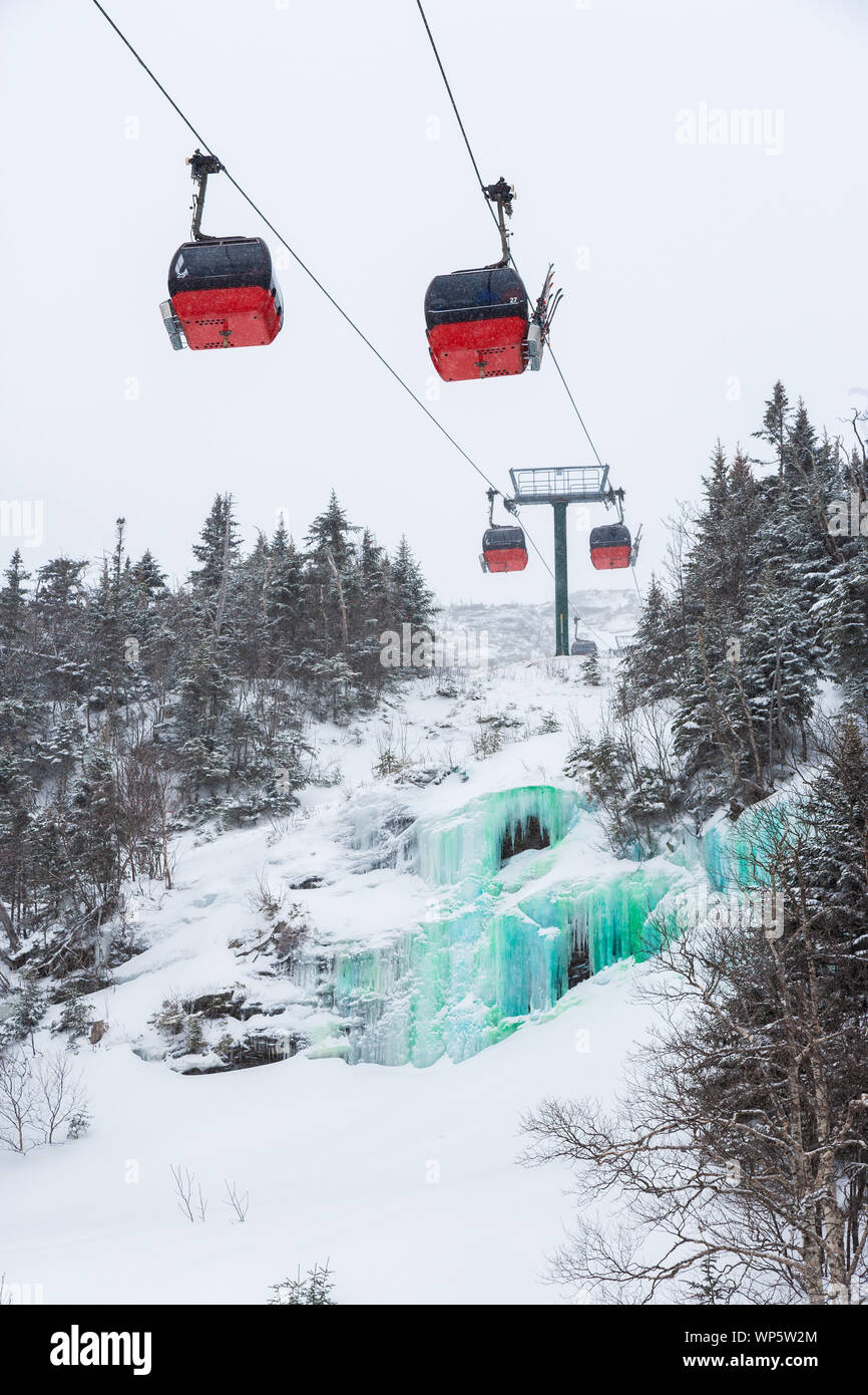 Stowe, VT, USA - Mar 17, 2005: The gondola lift to the top of the Stowe Mountain Resort over a green dyed waterfall for St. Patricks Day Stock Photo