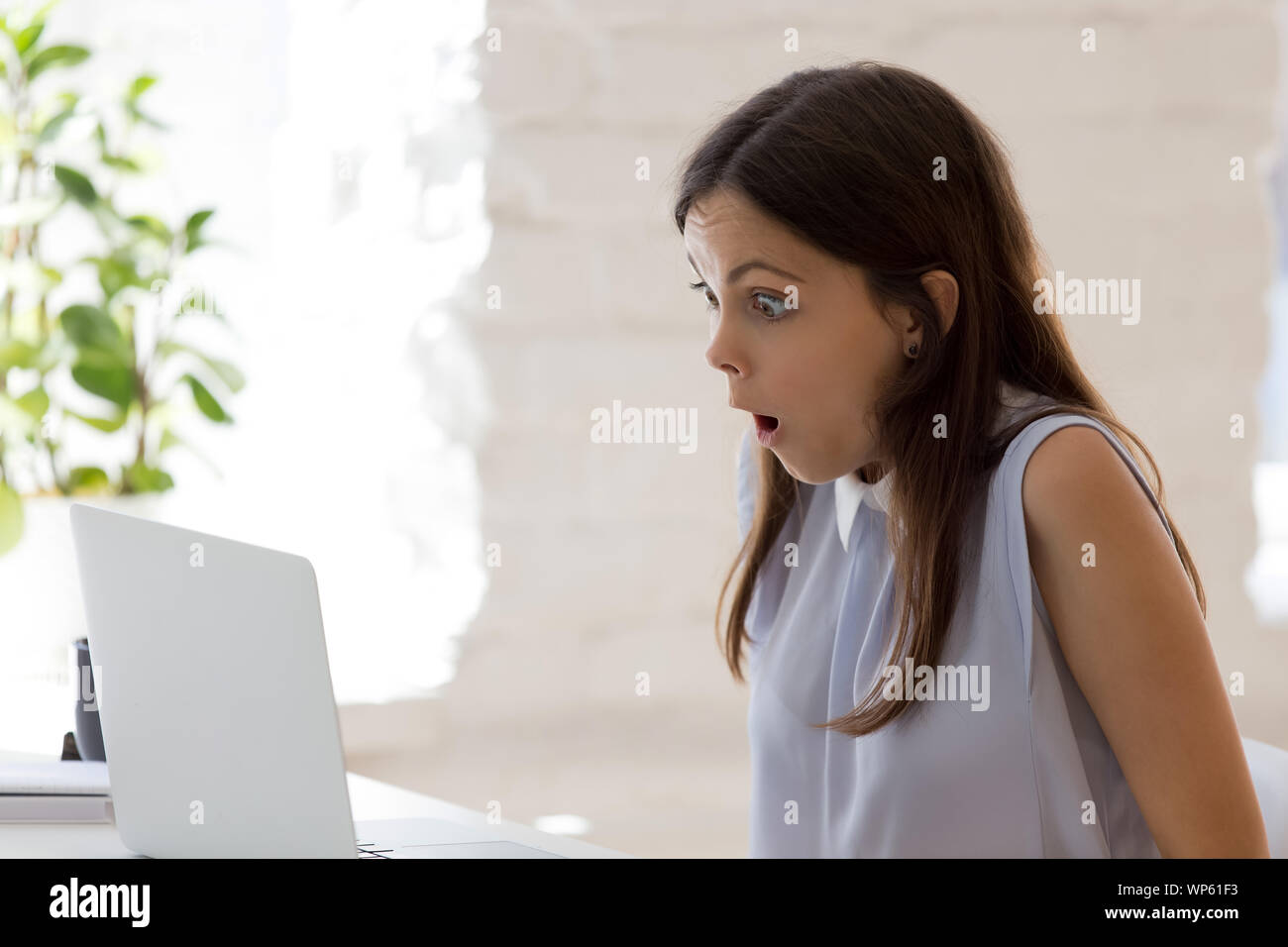 Shocked young woman read unbelievable news on laptop Stock Photo