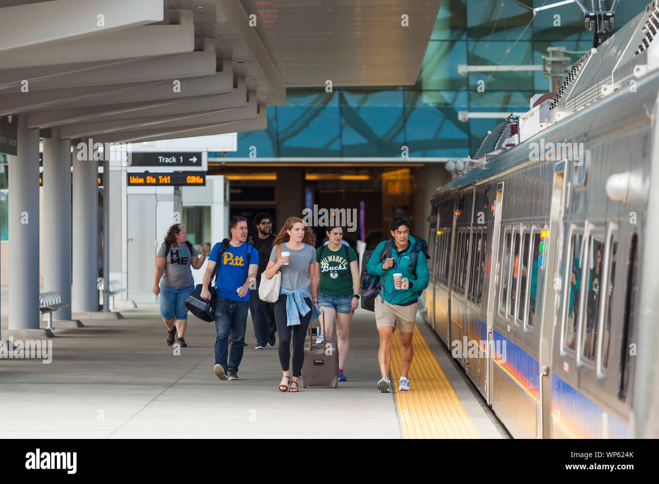 Travelers walk out to the light rail train, bound for Union Station, at